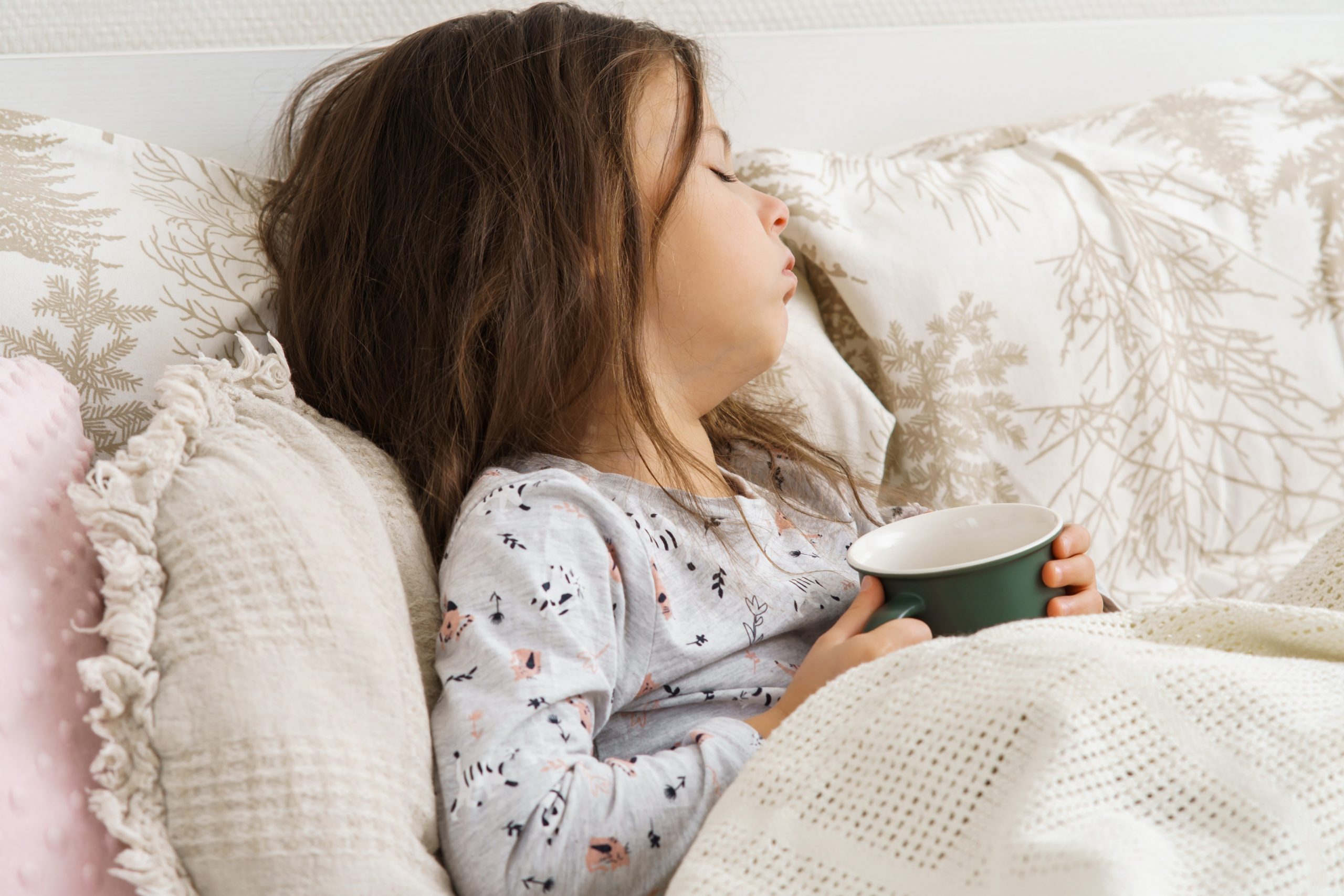 Bolna deklica kašlja in pije čaj