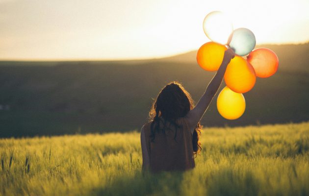 Ženska na travniku drži v rokah balone