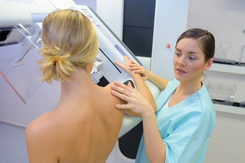 Ženska med mamografijo, pri čemer ji pomaga medicinska sestra