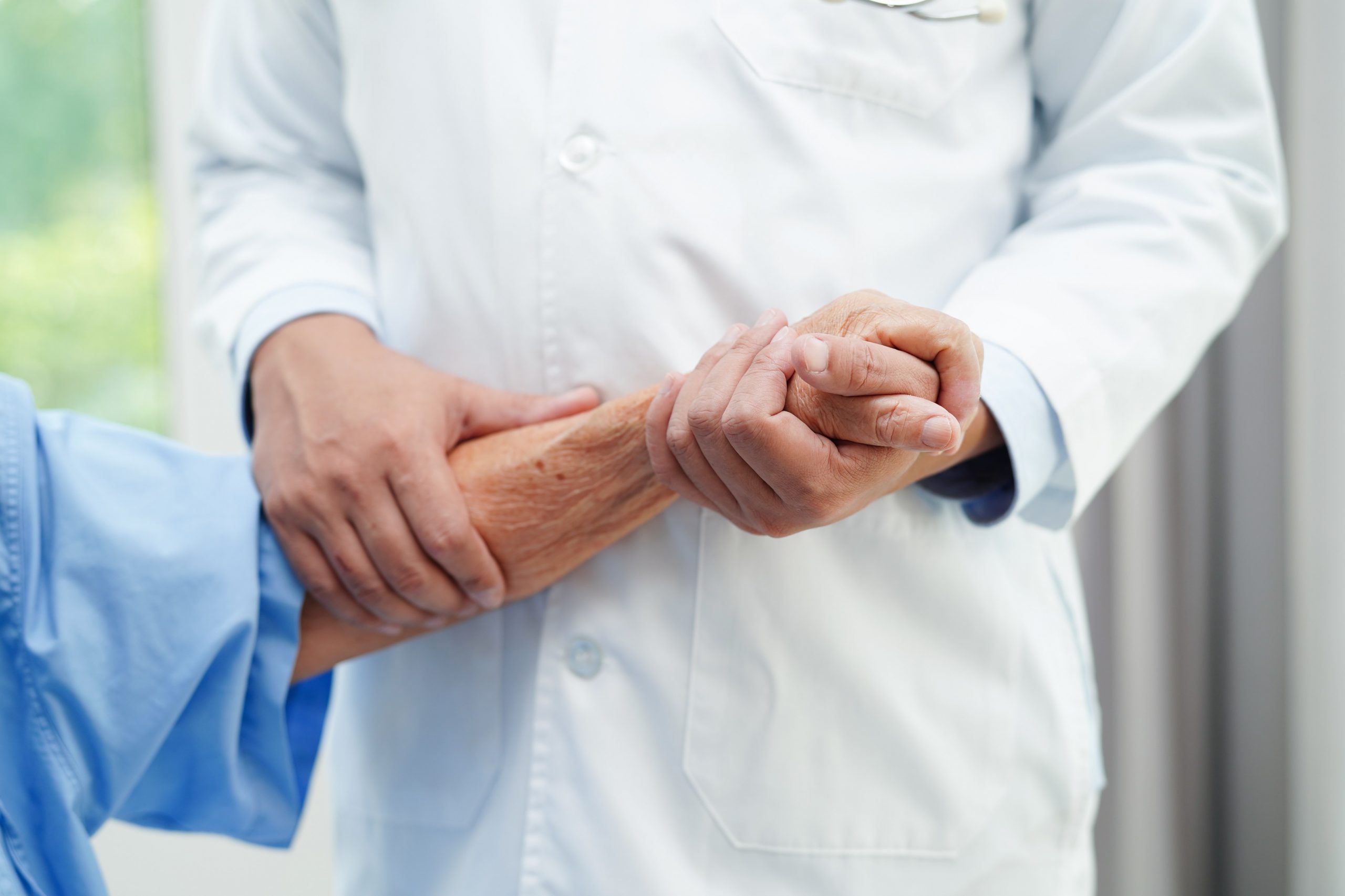 Zdravnik drži za roko starejšo osebo