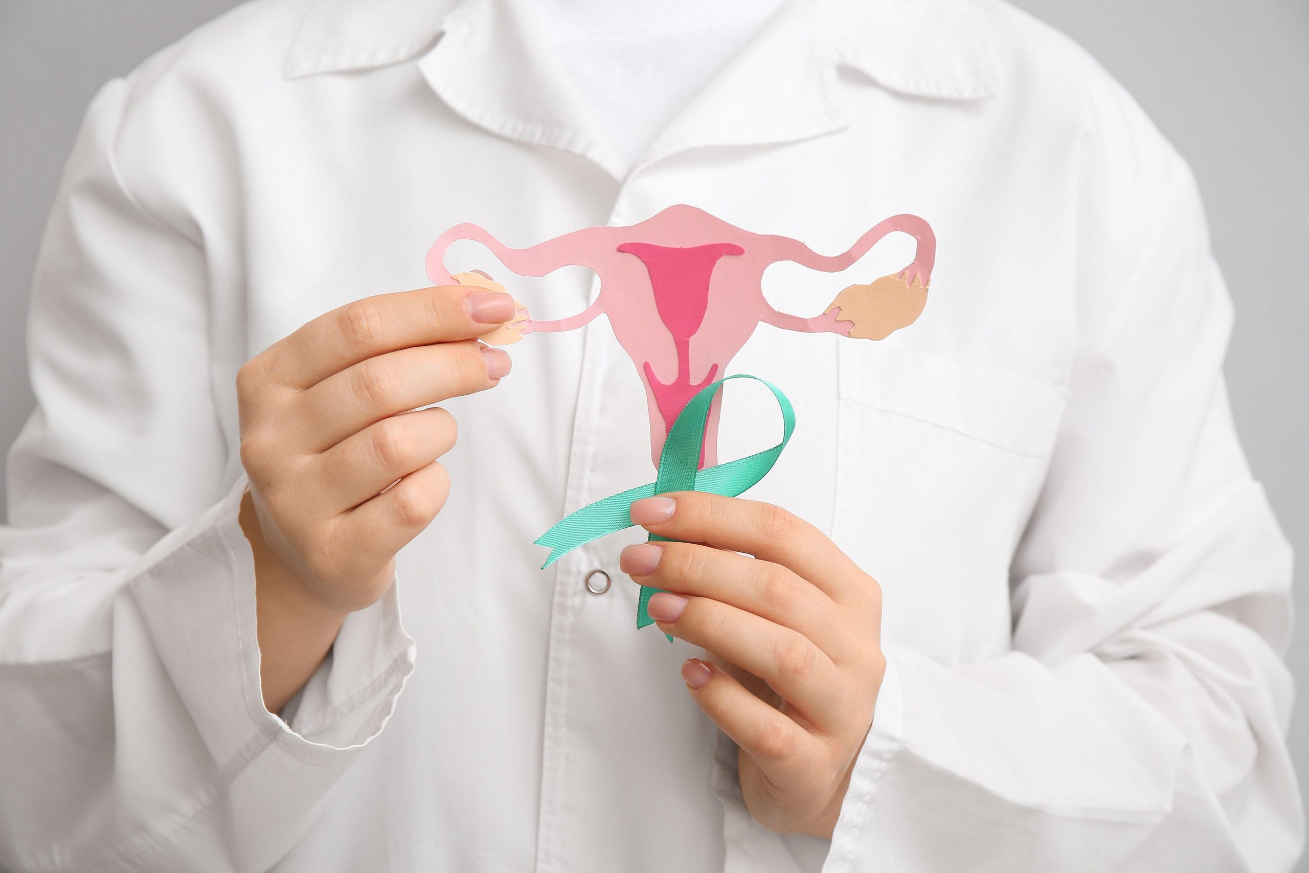 Zdravnica drži turkizno pentljo s papirnato maternico. Mesec ozaveščanja o zdravju materničnega vratu.