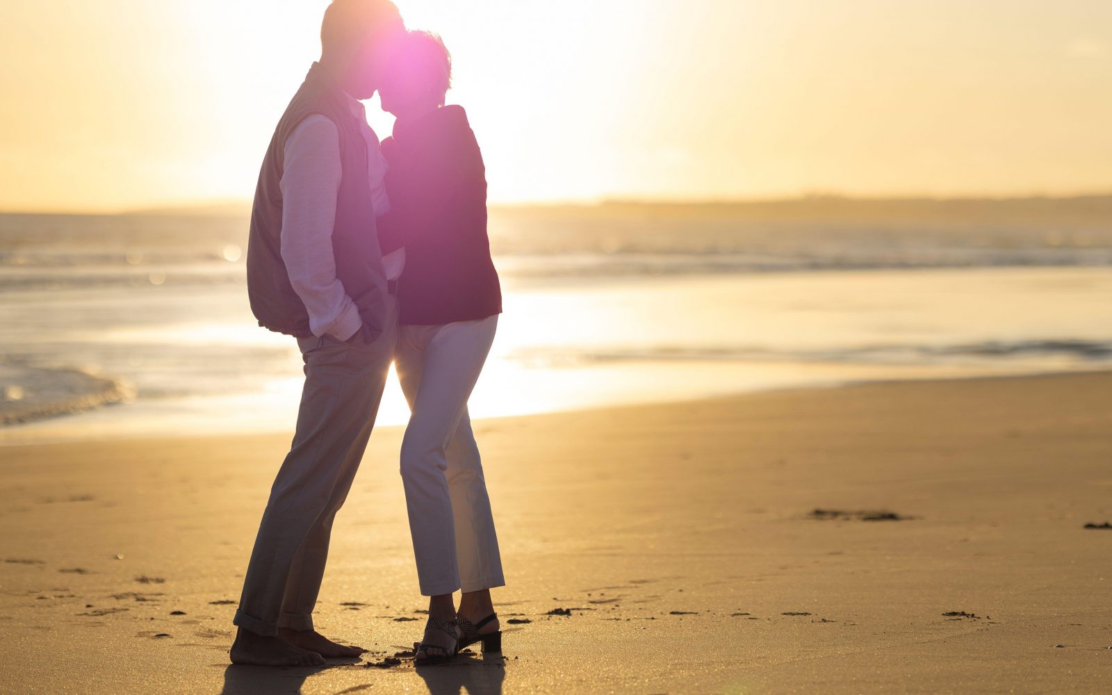 Zdrav starejši par uživa na plaži ob sončnem zahodu