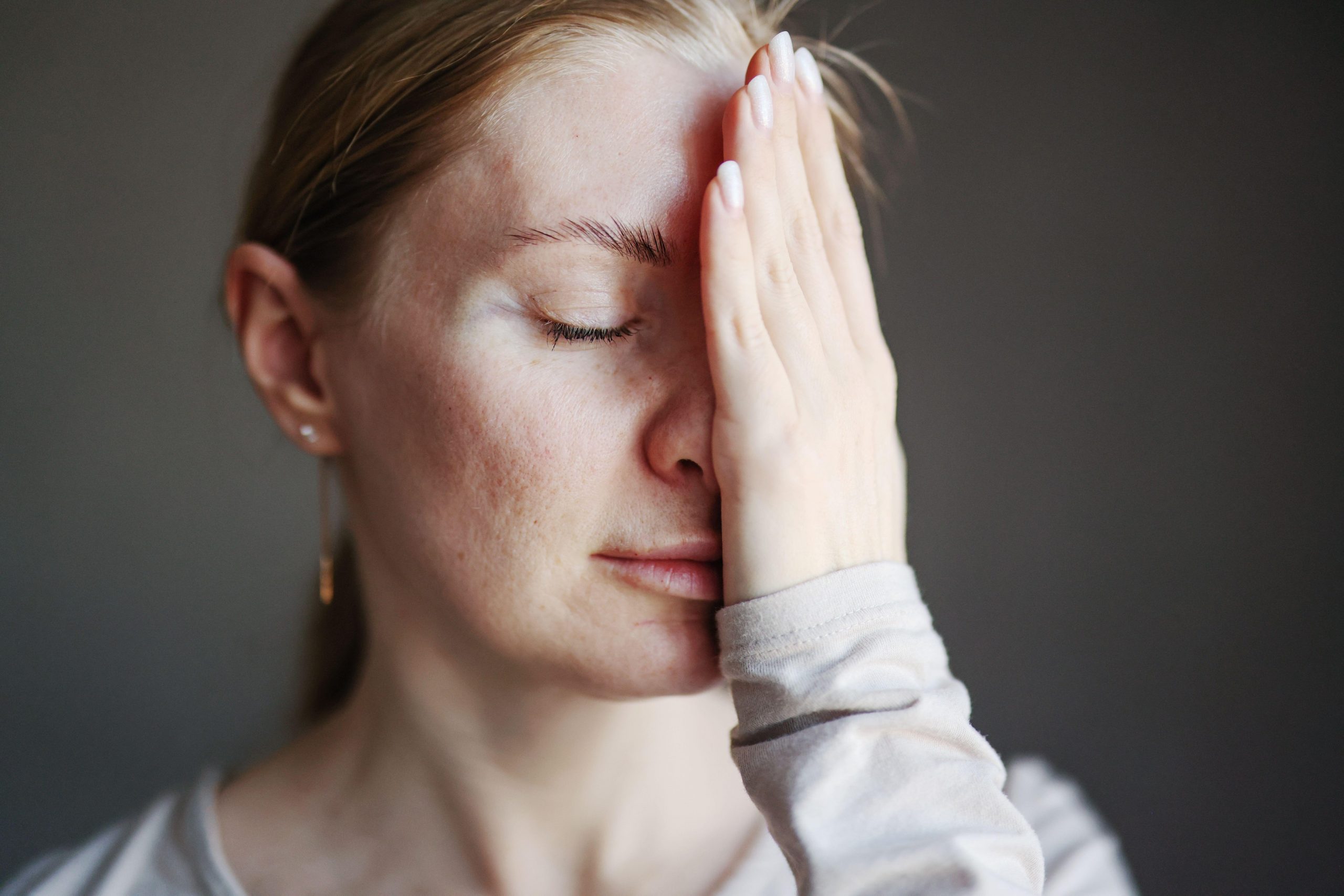 Ženska se drži za obraz; simbolika nege problematične kože