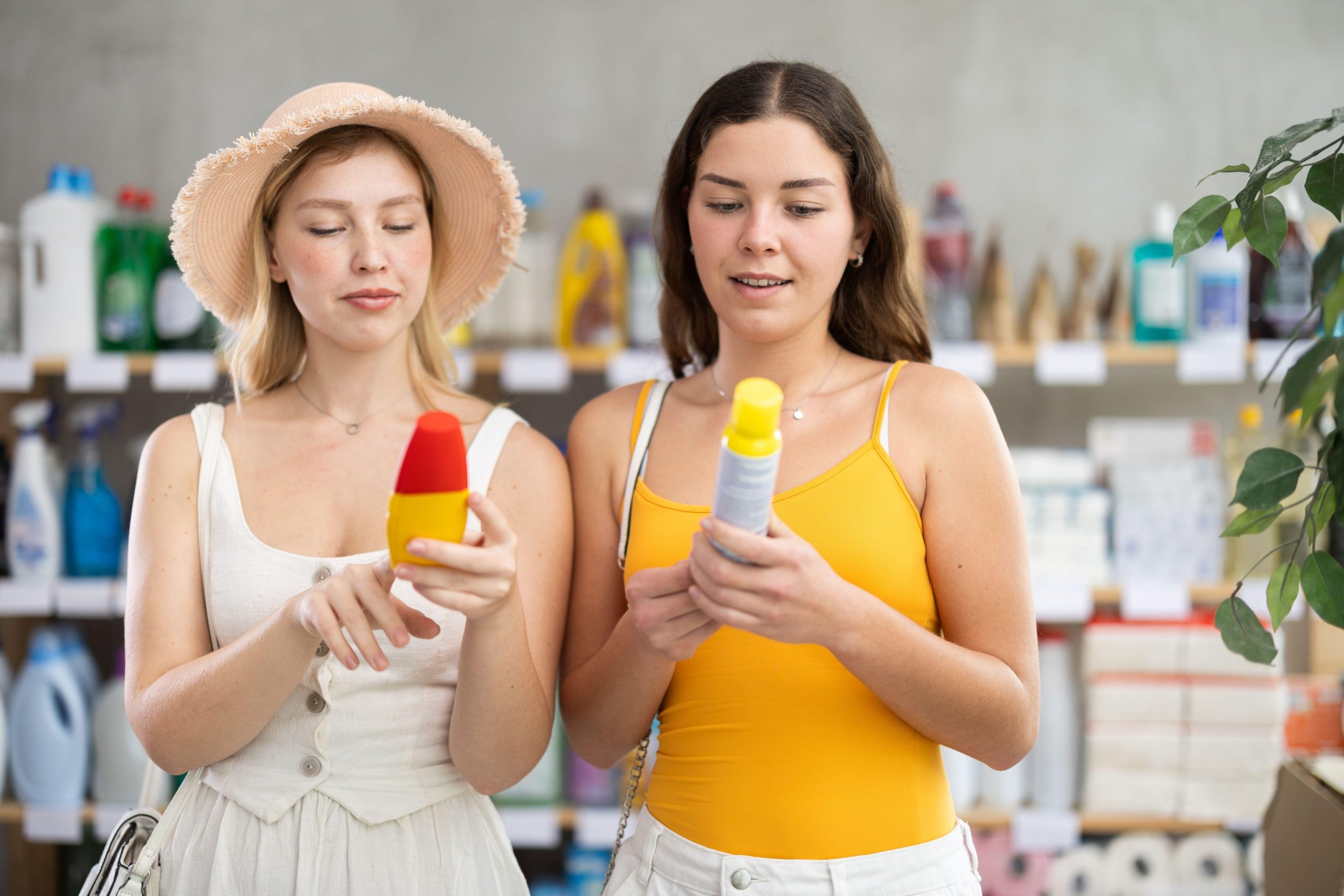 Dve mladi ženski v trgovini izbirata repelent proti komarjem in drugim insektom in bereta sestavine na embalaži.