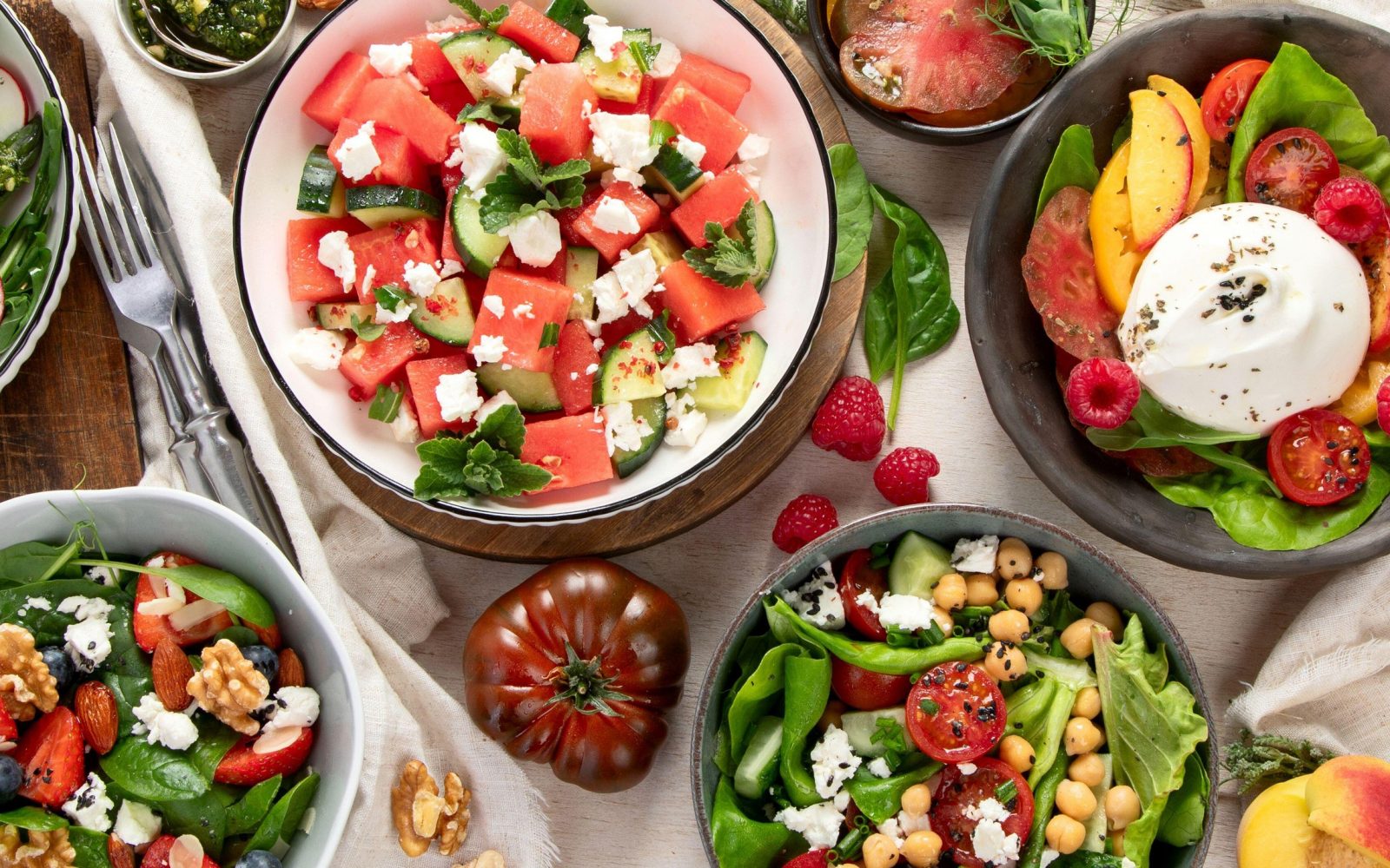 Različne poletne solate iz lokalnih sezonskih eko - lubenica, grah, paradižnik, borovnice, burrata, breskve, zelišča, oreščki