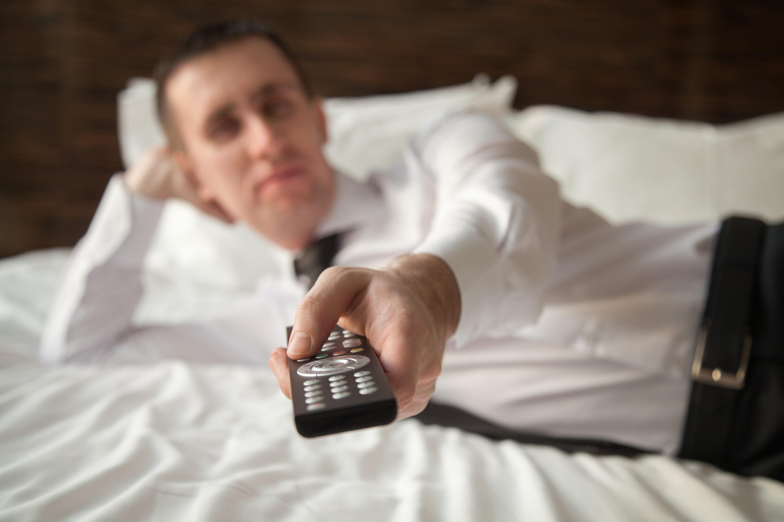 poslovni moški v hotelu drži v rokah daljinski upravljalnik