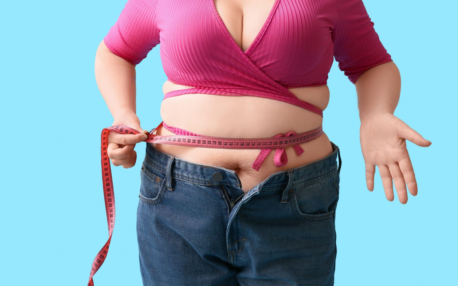 Ženska s prekomerno telesno težo si meri obseg pasu