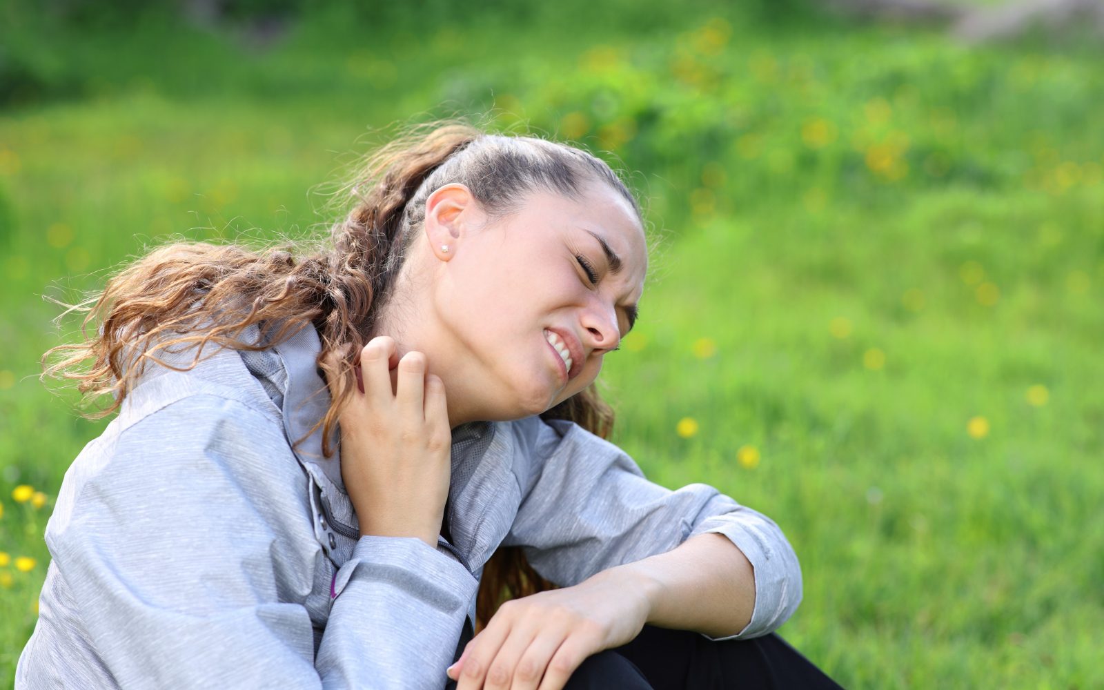 Mlada ženska se praska po vratu po piku komarja.