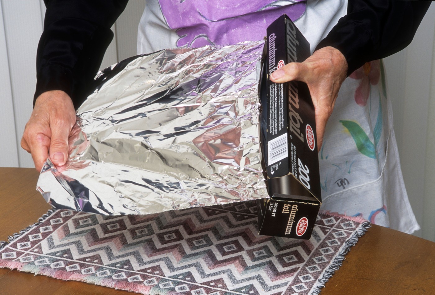 Oseba drži aluminijasto folijo – razlaga, kaj se zgodi, če jo pogoltnemo, in kdaj je nujno poiskati zdravniško pomoč