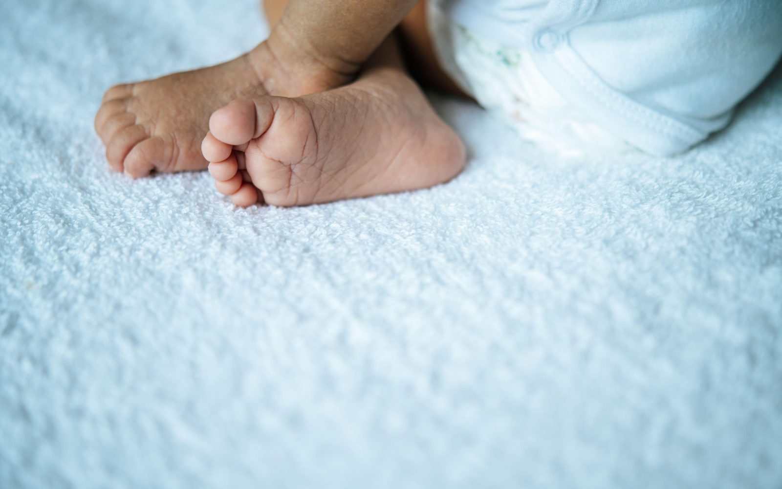 Novorojenčkove nogice na beli odeji.