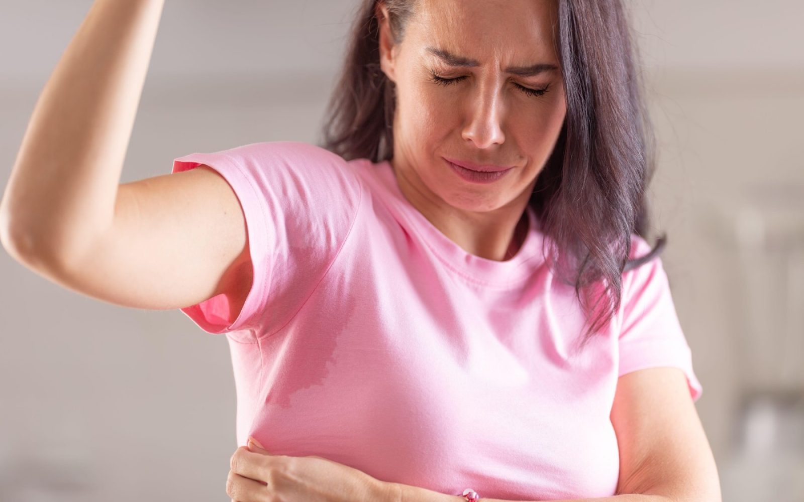 Ženska doma preverja telesni vonj z oblačilom kot del testa za svežino.