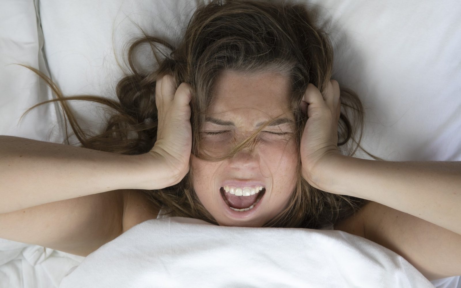 Nenaspana ženska leži v postelji.