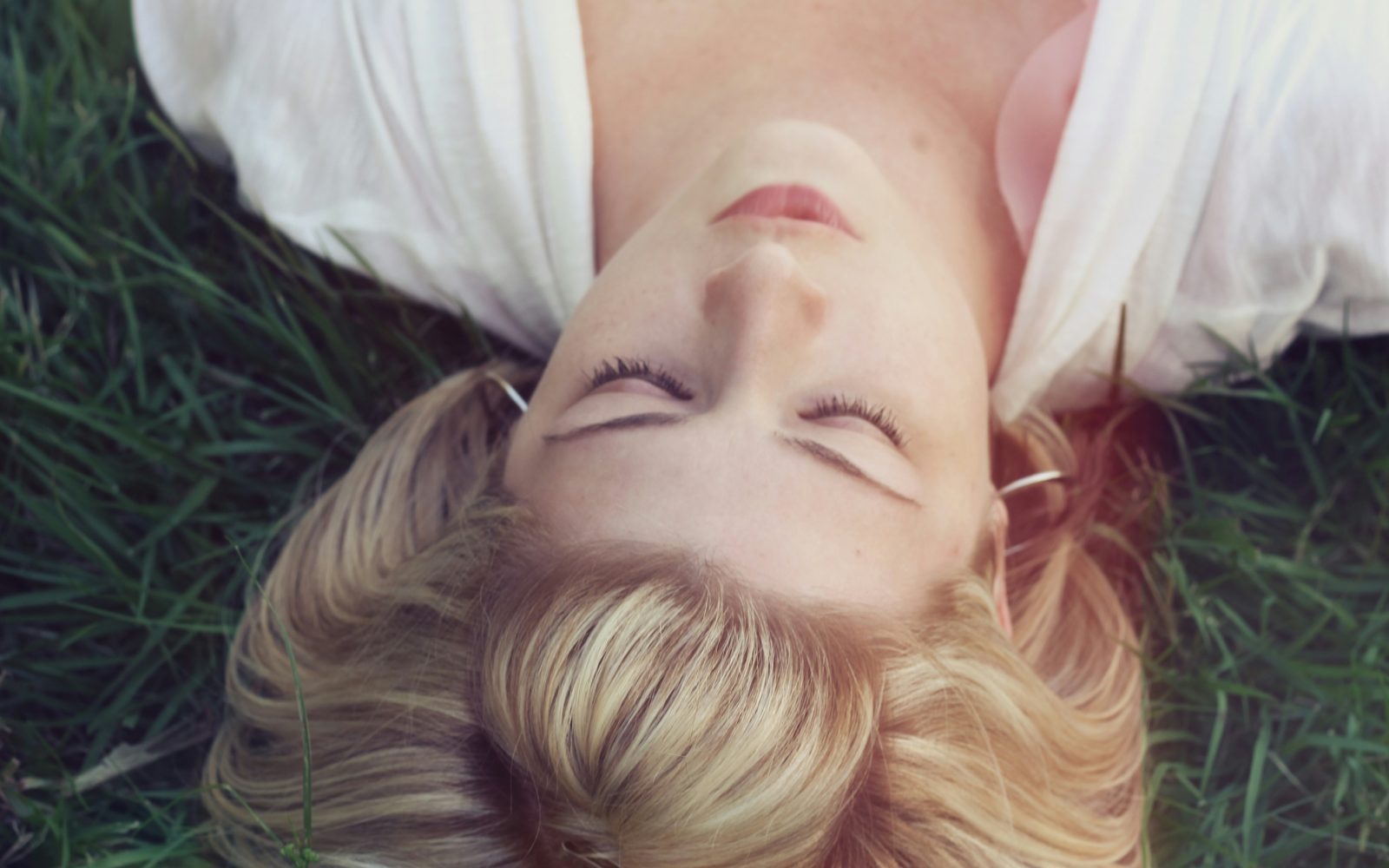 ženska z uhani leži v travi
