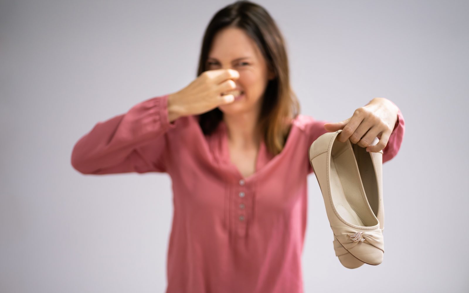Ženska v rokah drži balerinke, ki imajo neprijeten vonj