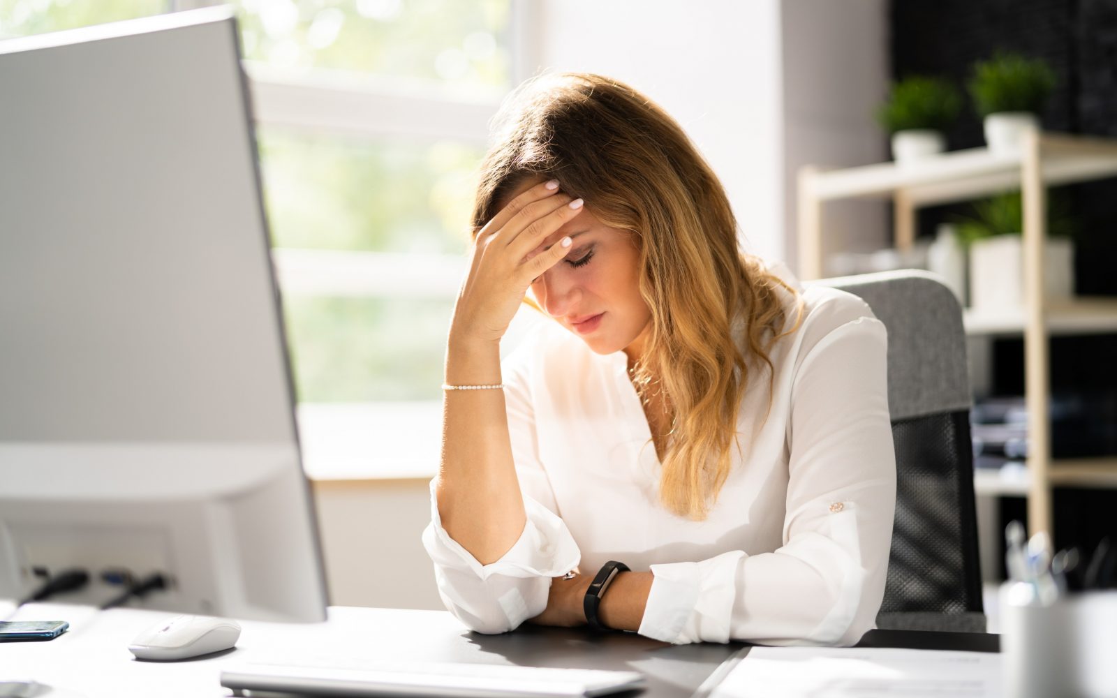 Utrujena ženska se drži za glavo