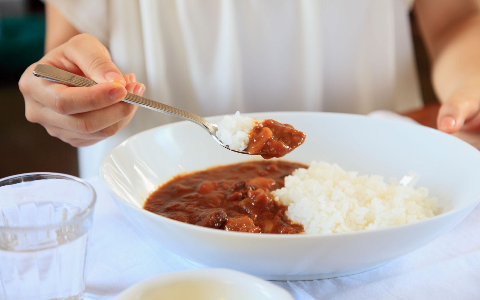Oseba je riž z omako iz belega krožnika – članek o arzenu v rižu in tveganju za zdravje.