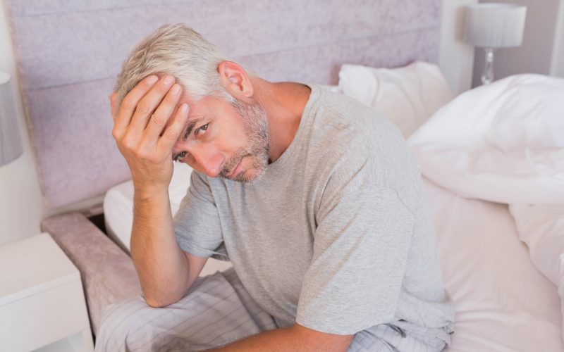 Moški se drži za glavo, je utrujen, utrujenost je eden od tako imenovanih b simptomov