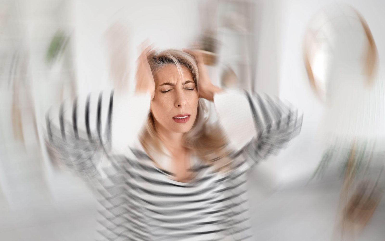 
Ženska, ki si drži glavo in trpi zaradi čustvenih nihanj in anksioznosti v perimenopavzi.