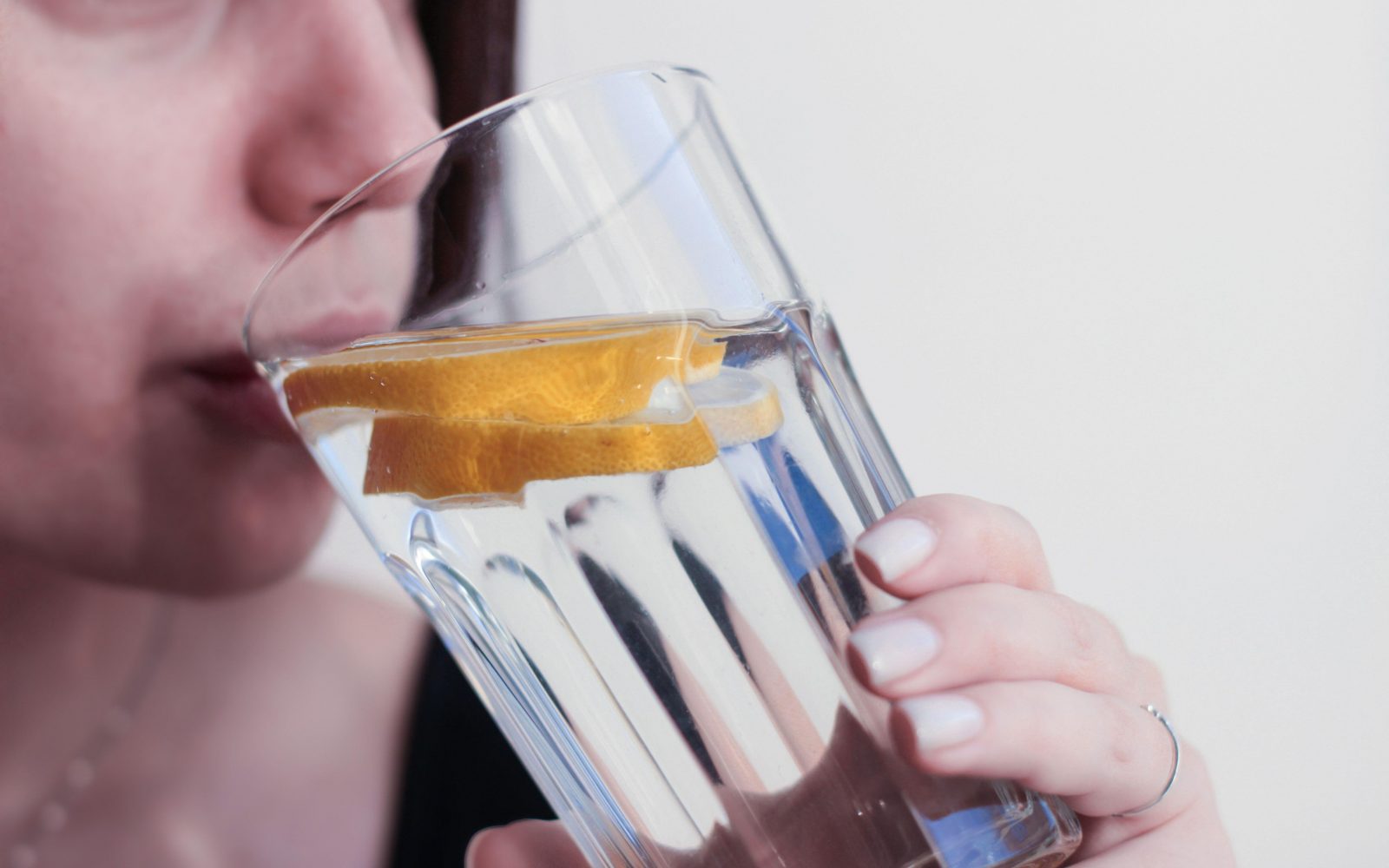 Mlada ženska pije vodo z limono iz steklenega kozarca namesto obroka, ker je na postu, ki dovoljuje le pitje vode.