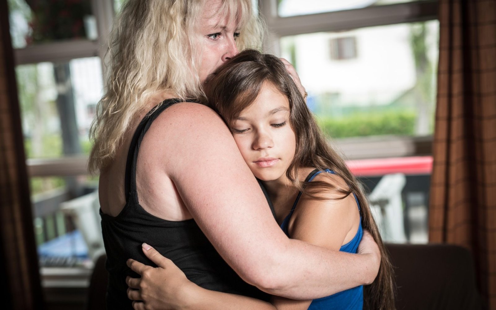 Mama tolaži najstniško hčer v dnevni sobi doma