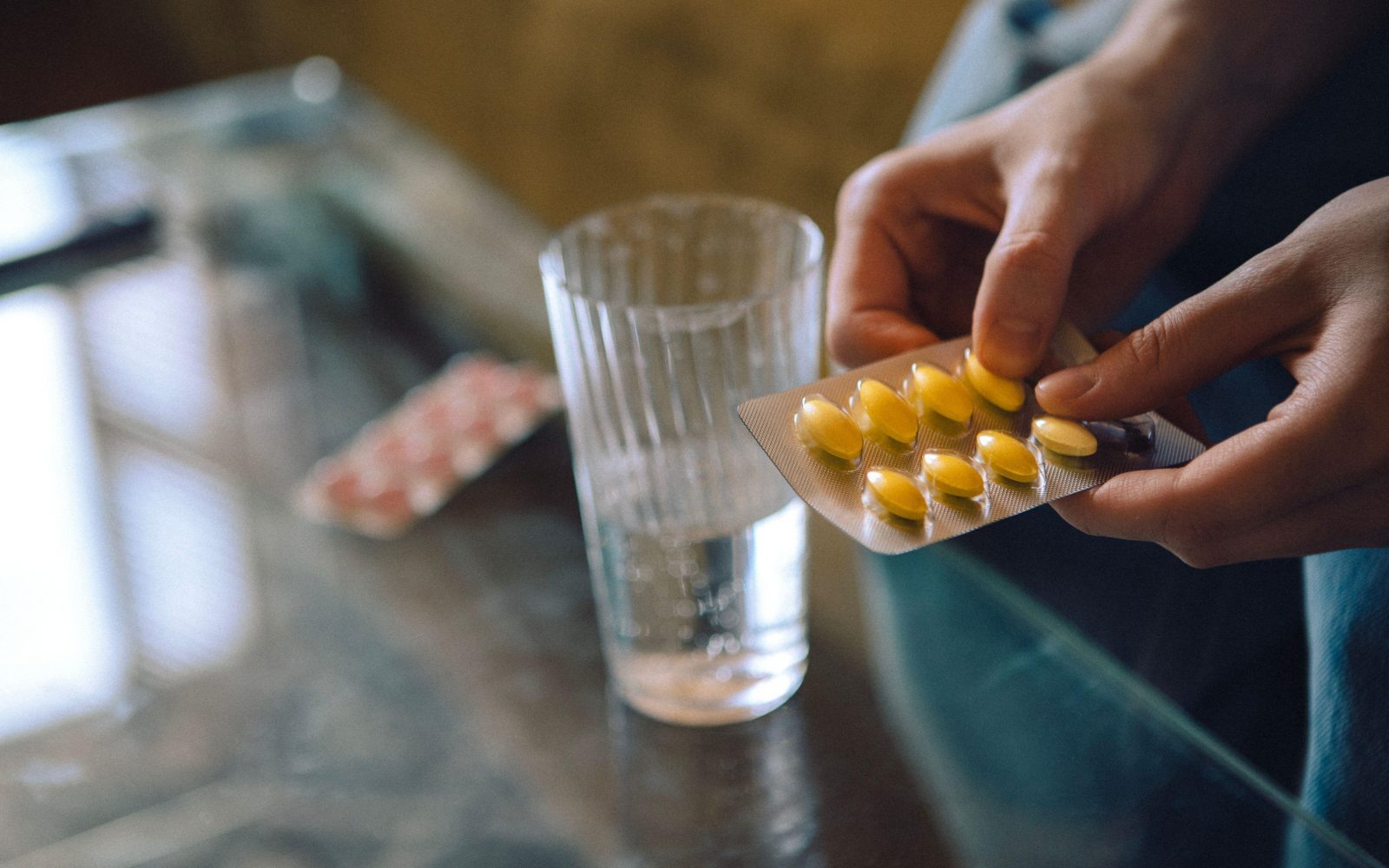 Ženska, ki zavita v odeje jemlje zdravilo proti bolečinam brez recepta - varna uporaba zahteva, da preberemo navodila za uporabo in se jih dosledno držimo