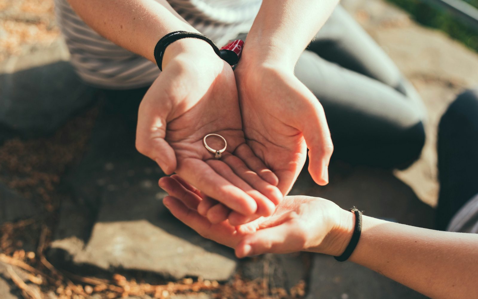 nekdo v dlaneh drži prstan, simbolika razhoda oziroma razveze. Zraven je pe ena roka, simbolika čustvene podpore