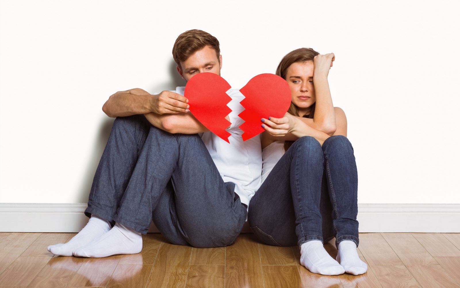Mlad par, moški in ženska, v rokah držita pretrgano srce, simbolika razhoda, razveze, konca odnosa