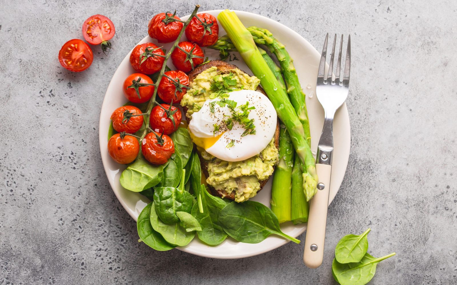 Uravnotežen krožnik z zelenjavo, jajcem in avokadom – primer zdravega obroka za dolgotrajno sitost.