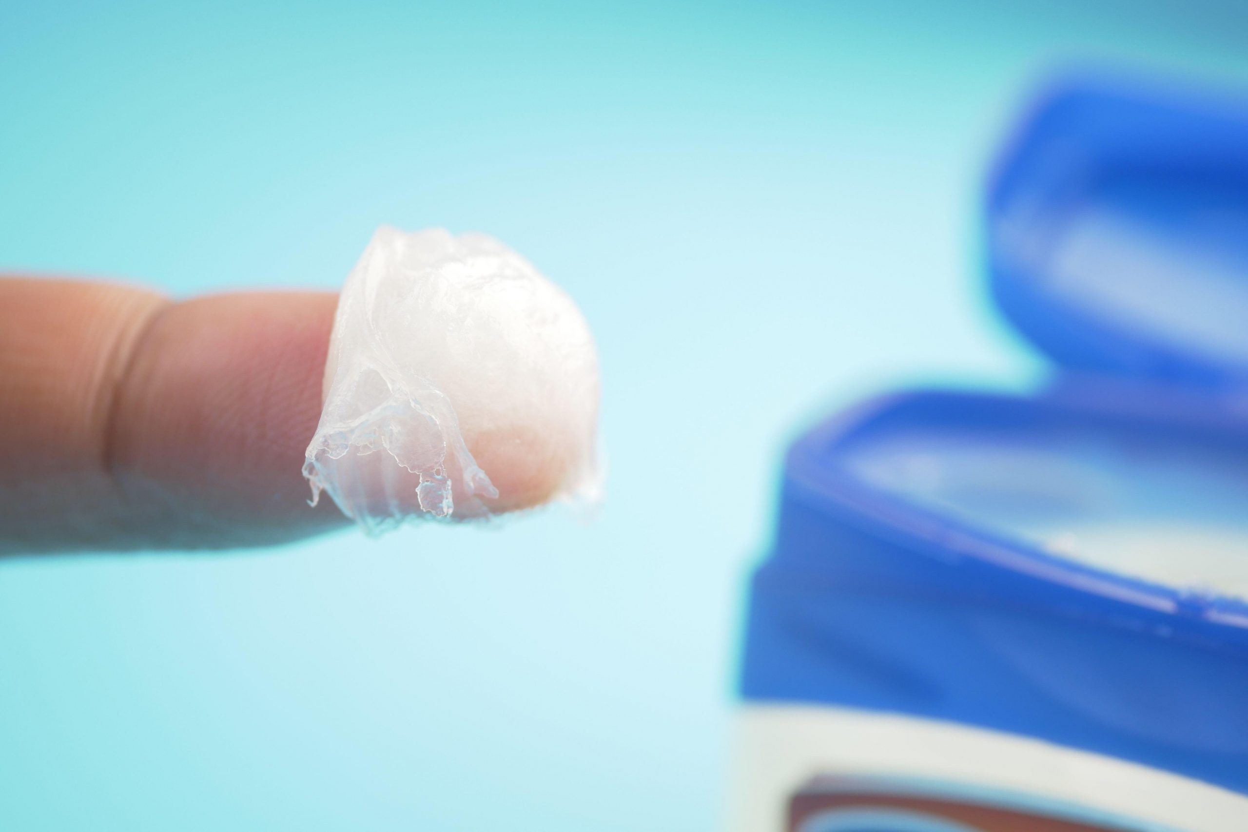 Vazelin na prstu, pripravljen za nanos na obraz kot del nočne rutine nege kože - intenzivna hidracija in zaščita kože s slojem vazelina.