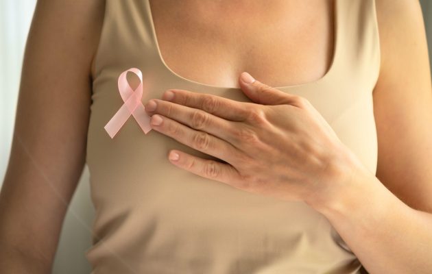 Nližnji posnetek ženskega trupa, na majici je roza penmtlja, ozaveščanje o raku dojk