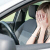 Ženska v avtu si prekriva roke z dlanmi