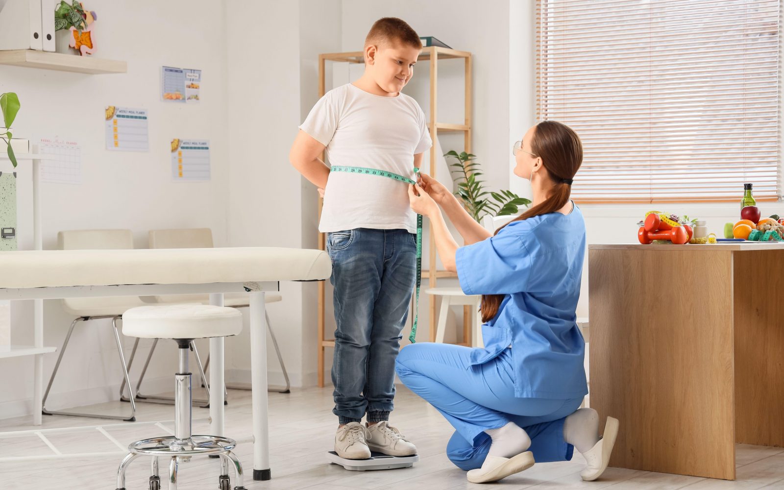 Medicinska sestra izvaja meritve pri prekomerno prehranjenem otroku