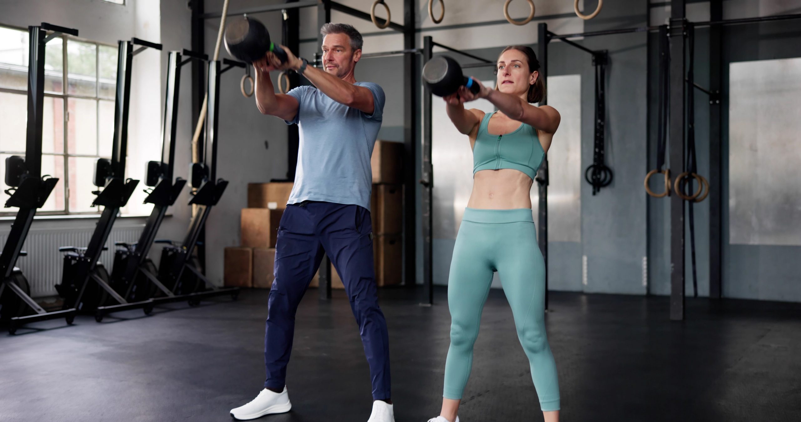 Moški in ženska v telovadnici delata vaje z utežmi