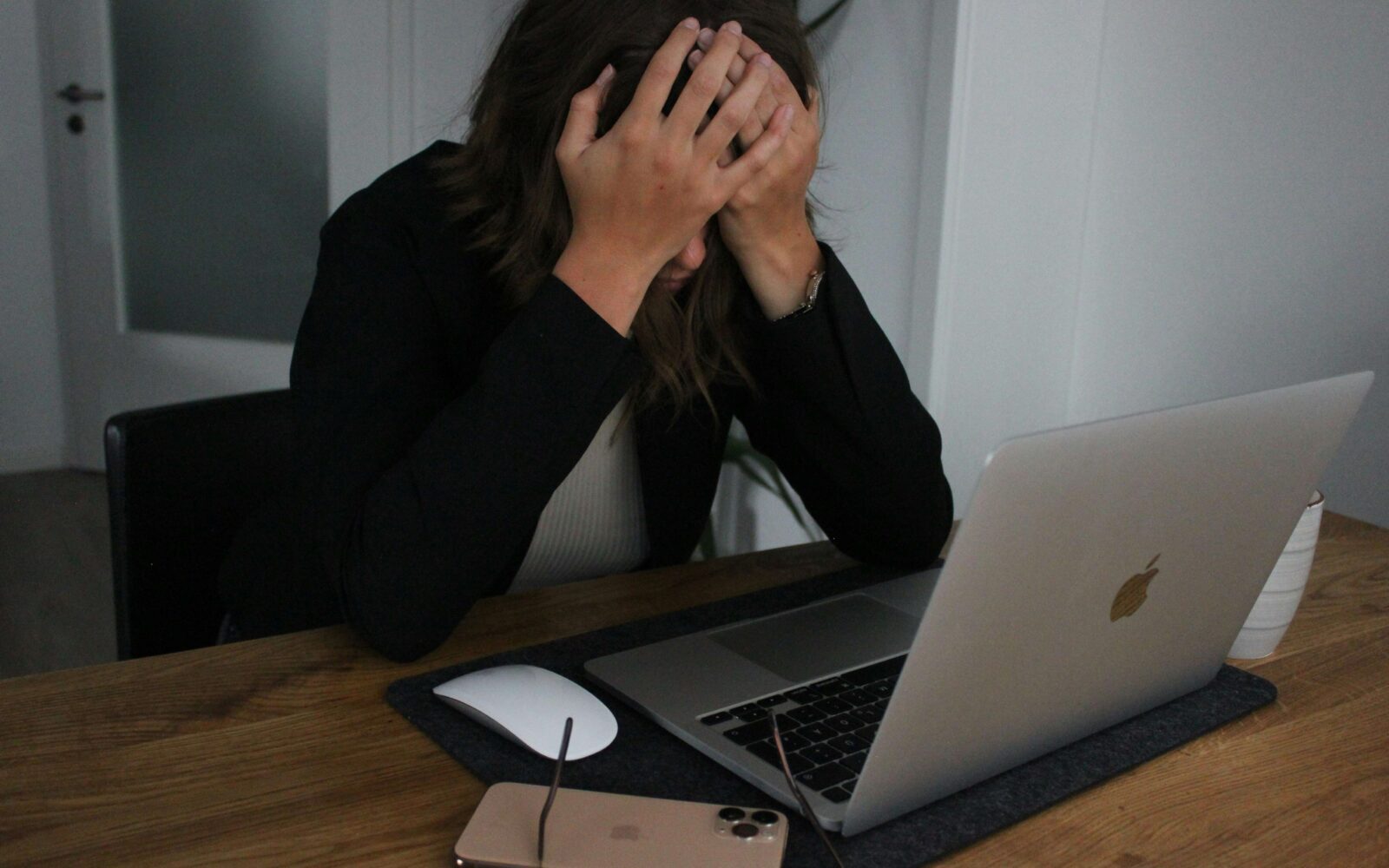 Ženska sedi za računalnikom in se drži za glavo, boli jo glava