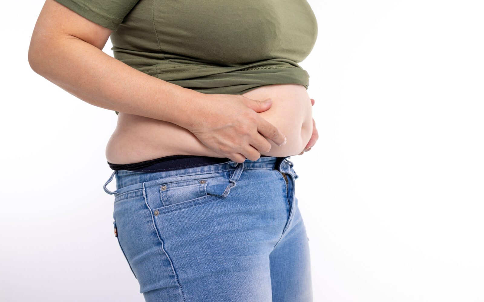 Ženska s PCOS, ki se drži za trebuh – značilno nabiranje maščob okoli trebuha pri PCOS.