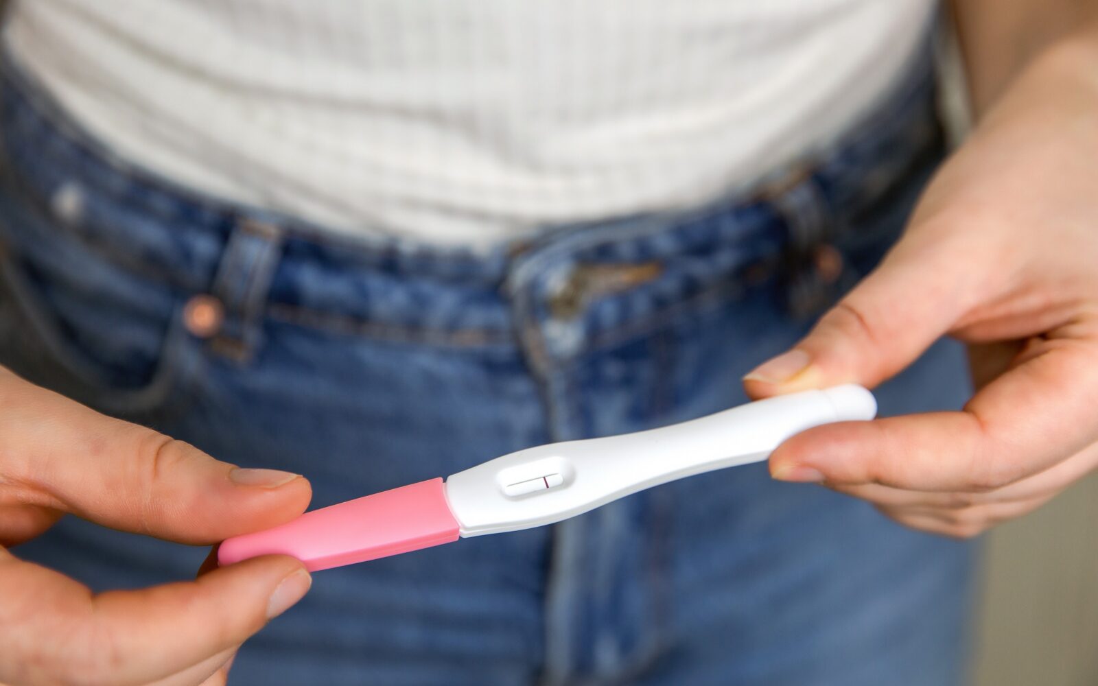 Mlada ženska v rokah drži negativen test nosečnosti