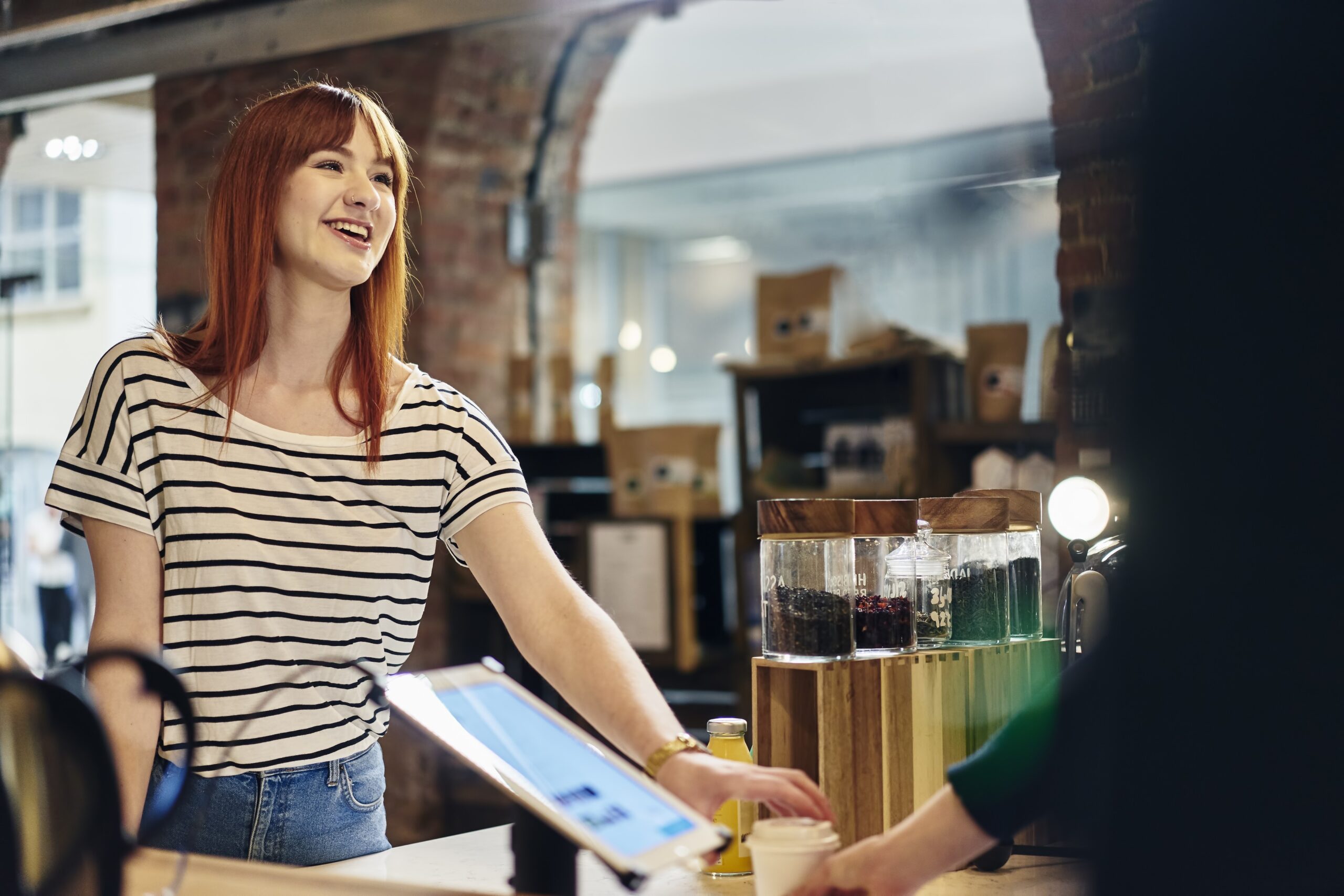 Nasmejana ženska v kavarni naroča kavo z nasmehom, vludni pozdrav in manire štetjejo