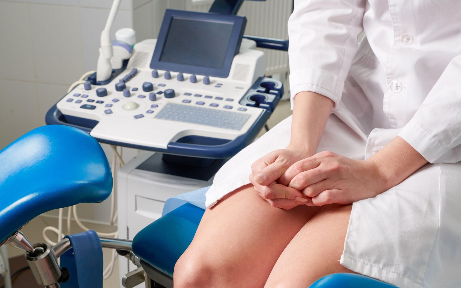 Ženska sedi in čaka na ginekološki pregled. Je živčna, saj stiska dlani