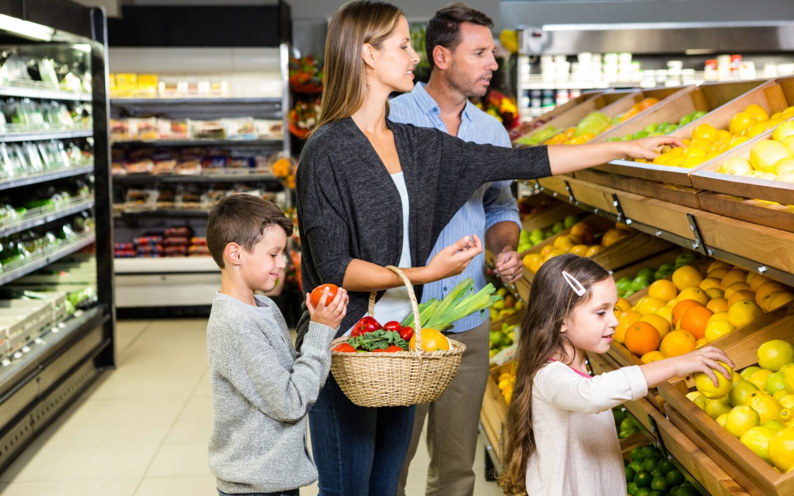Družina - mati, oče, sin in hči - nakupujejo sadje in zelenjavo