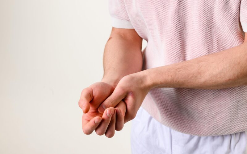 Moški se drži za roko - paraliza ene roke po kapi