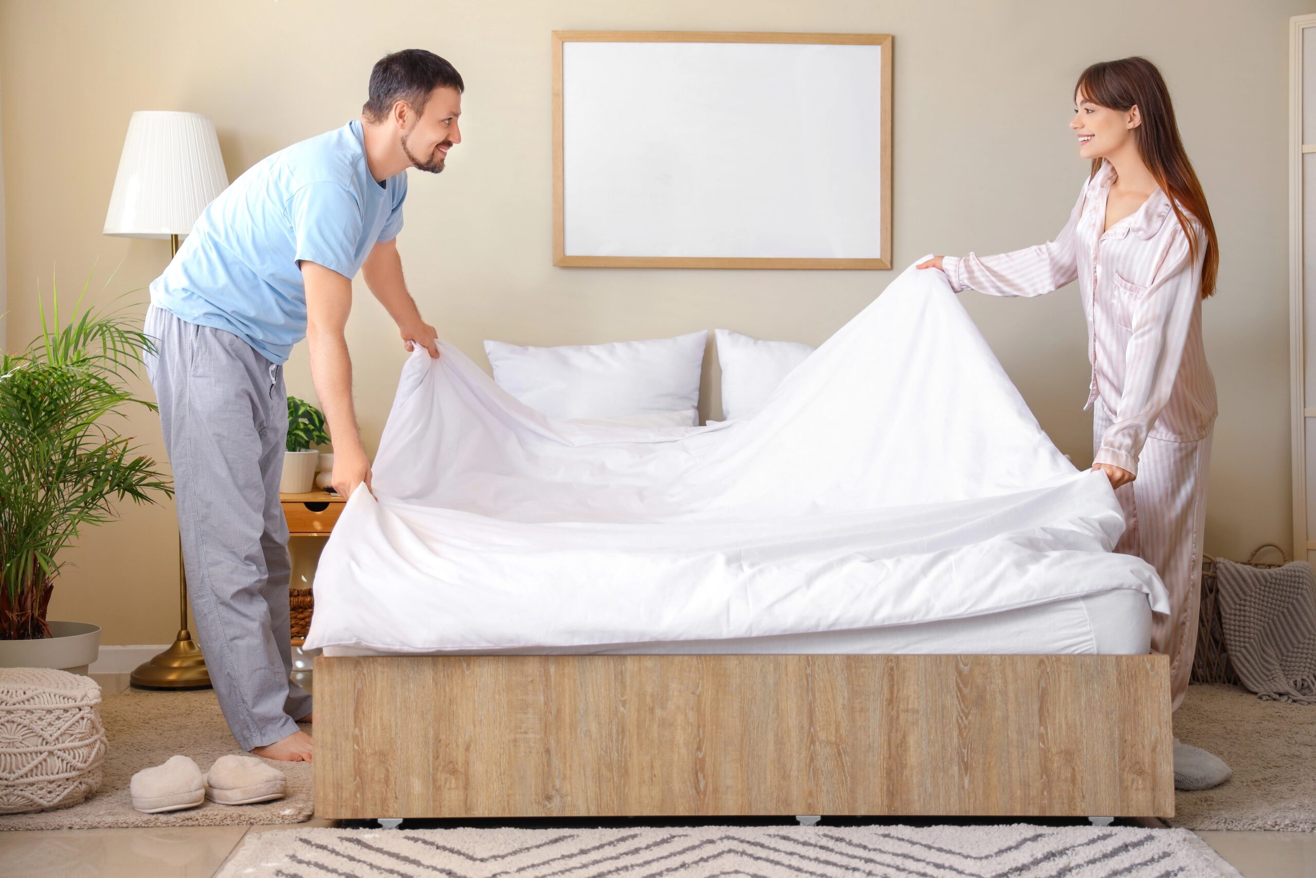 Ženska in moški zjutraj postiljata posteljo