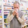 Prehlajen moški si briše nos in je v lekarni
