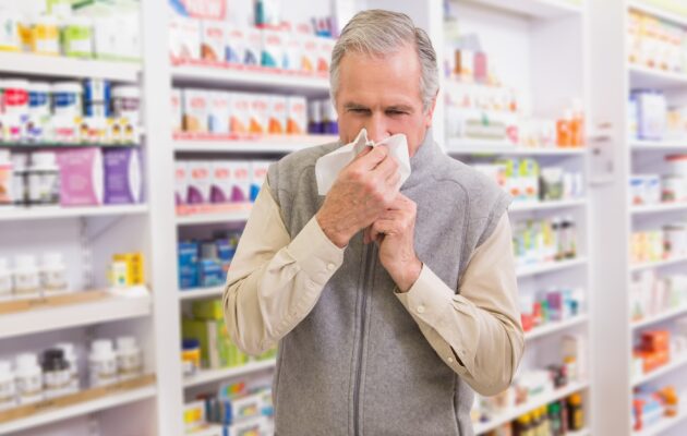 Prehlajen moški si briše nos in je v lekarni