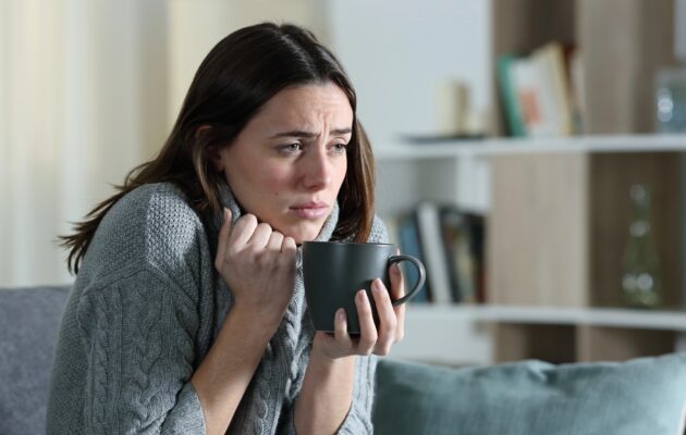 Žensko zebe, slabo se počuti, v rokah drži skodelico toplega napitka