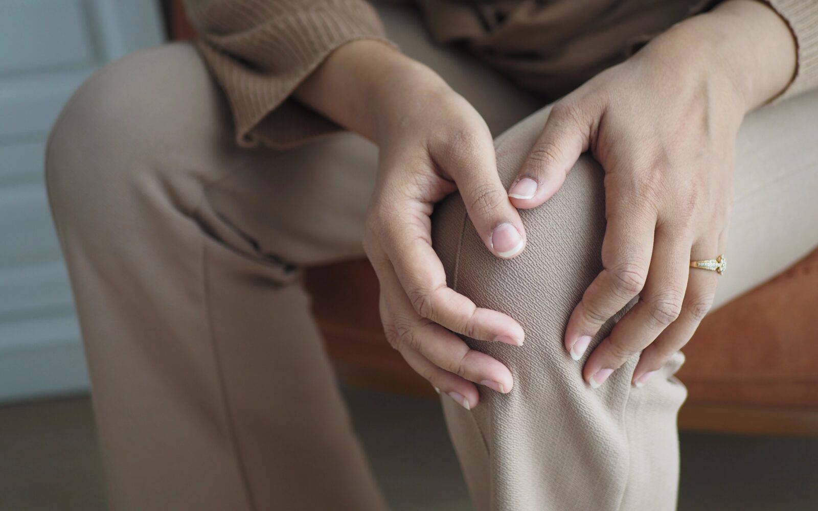 Ženska se drži za boleče koleno, pozimi se bolečine v sklepih lahko poslabšajo
