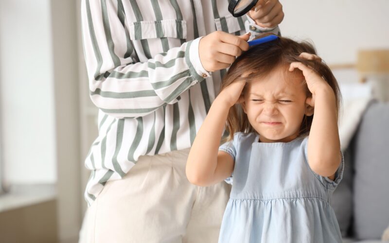 Malo deklico srbi glava zaradi naglavnih uši - si jo praska. Mati ji pregleduje glavo z gostim glavnikom