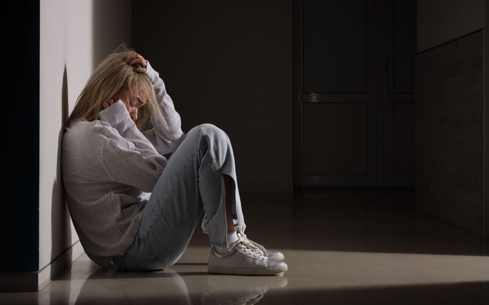 žalostna in depresivna ženska sedi na tleh