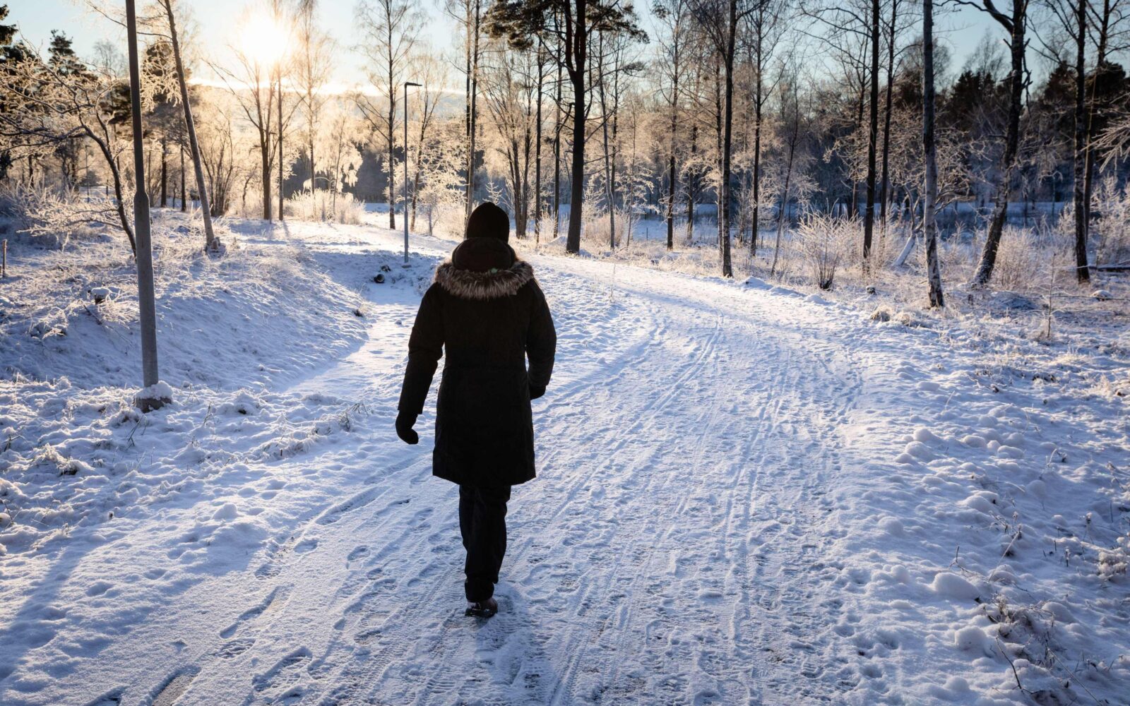 Toplo oblečena oseba je na jutranjem zimskem sprehodu