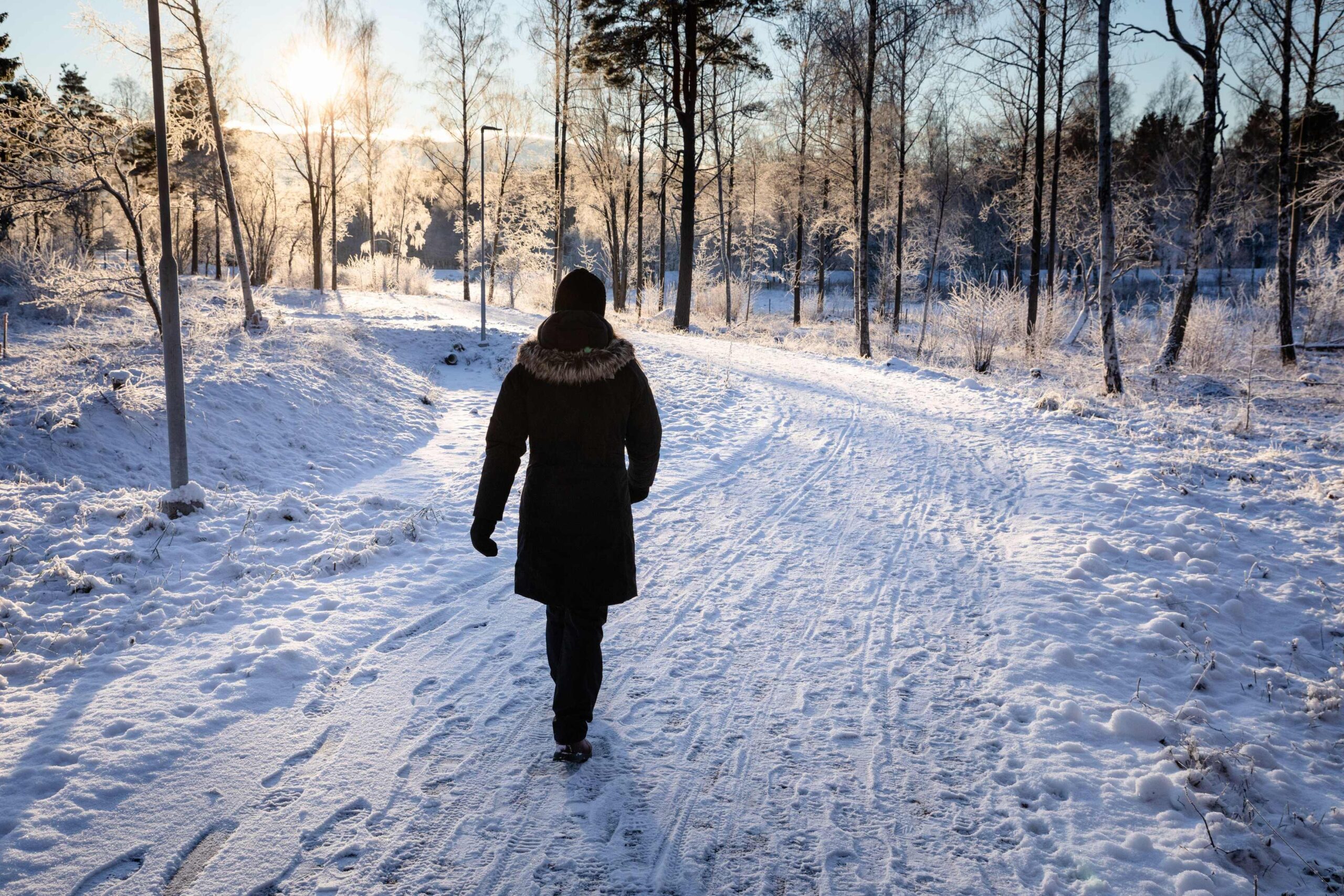 Toplo oblečena oseba je na jutranjem zimskem sprehodu
