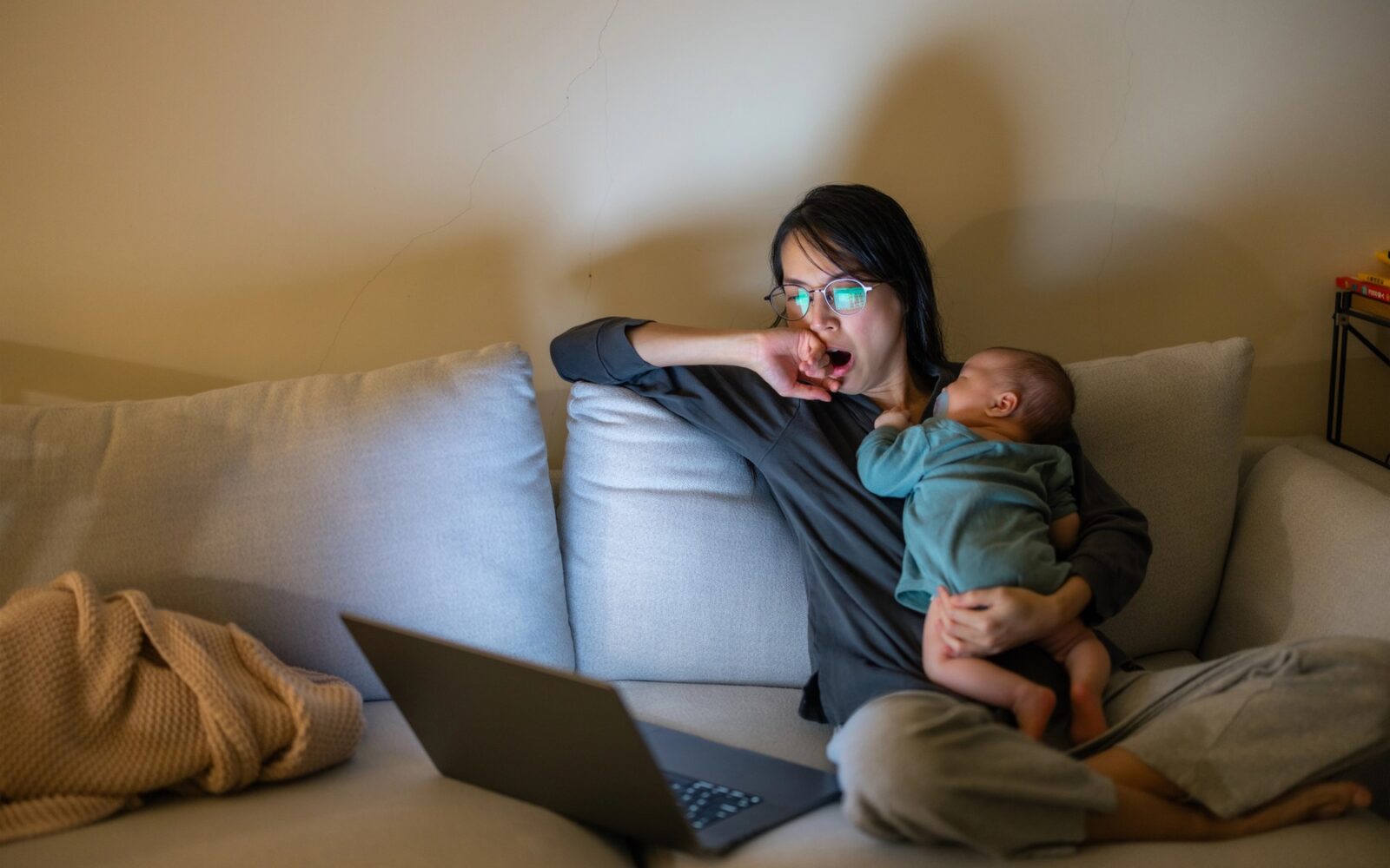 mama v naročju z dojenčkom, ki ne more spati, zato tudi ona ne spi in gleda v zaslon računalnika